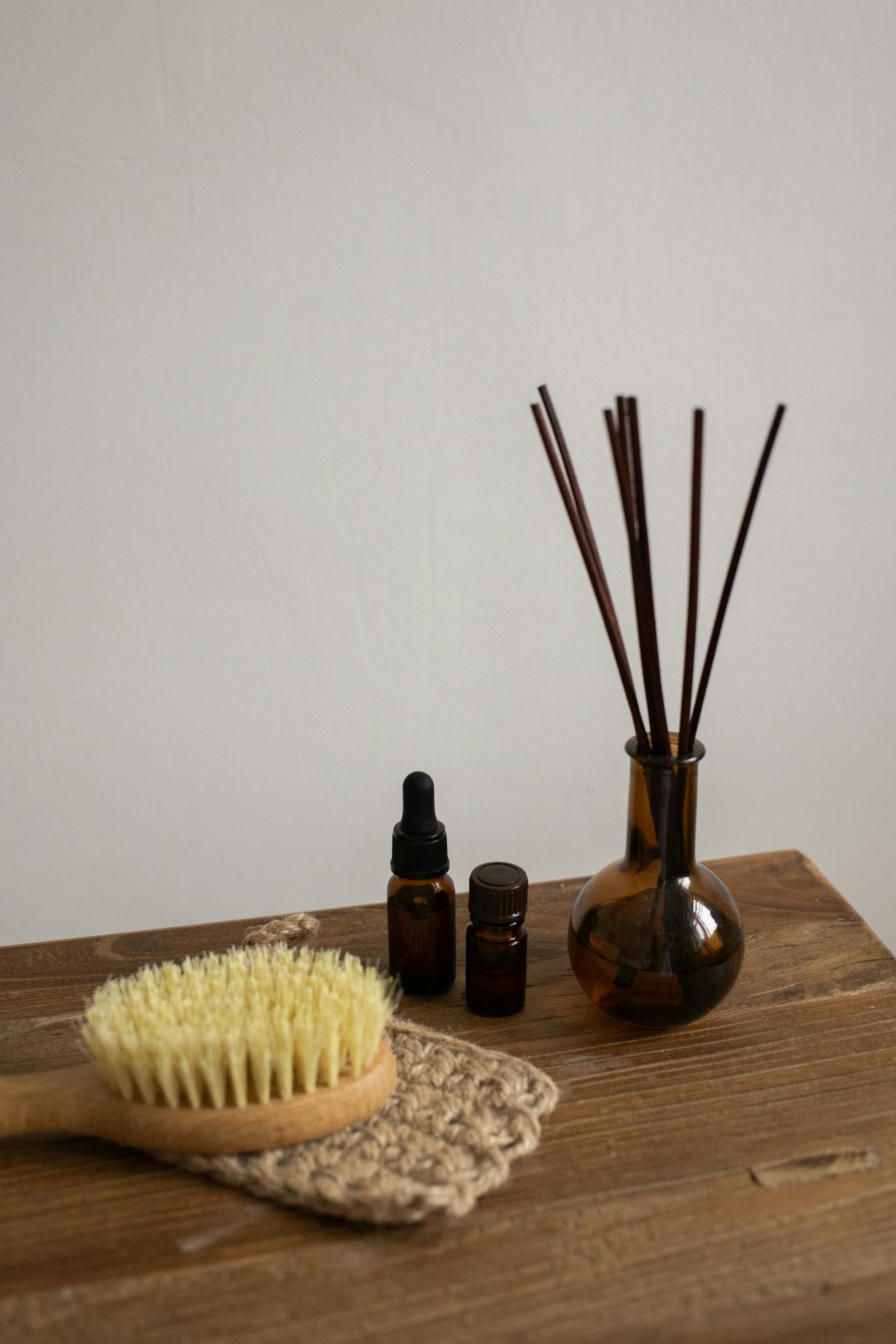 A minimalist display of aromatherapy bottles and a brush on a wooden table.