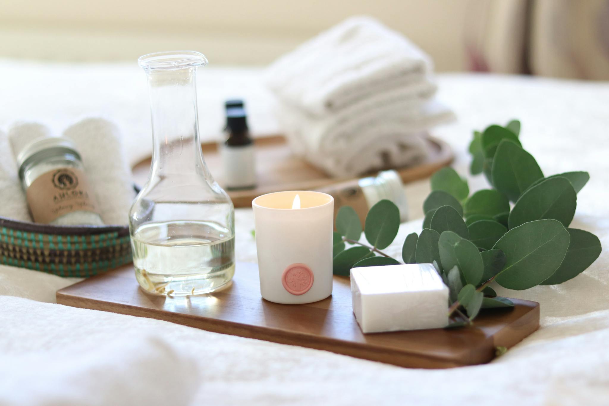 A serene spa-inspired setup featuring candles, essential oils, and eucalyptus leaves for a relaxing ambiance.
